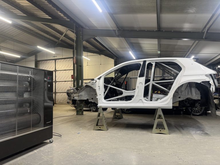 Rally car in a workshop where Airrex heater is keeping the space warm.